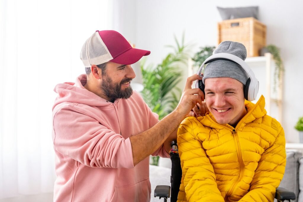 Happy disabled man listening to music using headphones with caregiver